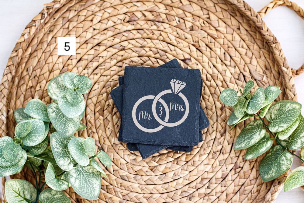 Wedding coaster featuring interlocked rings design on navy background with eucalyptus leaf decor.
