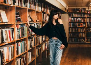 Person browsing books in a cozy library with wooden shelves and warm lighting.