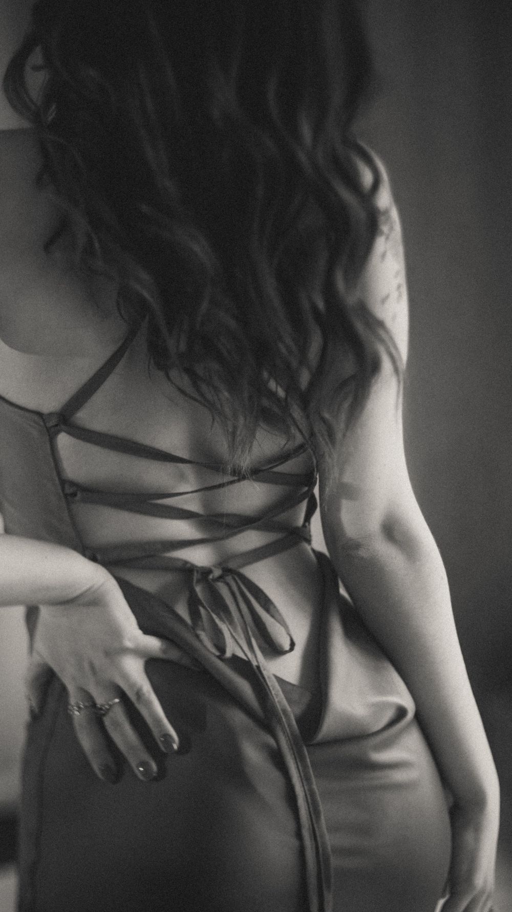 Artistic black and white photograph showing details of a dress being untied.