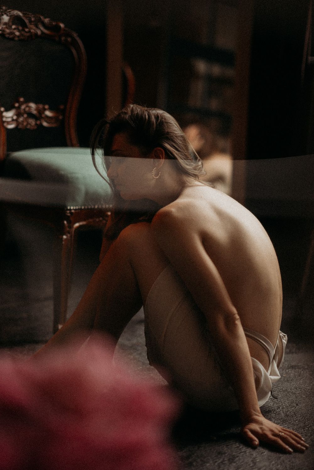 Artistic boudoir photography featuring dramatic lighting and shadows in a dark room.