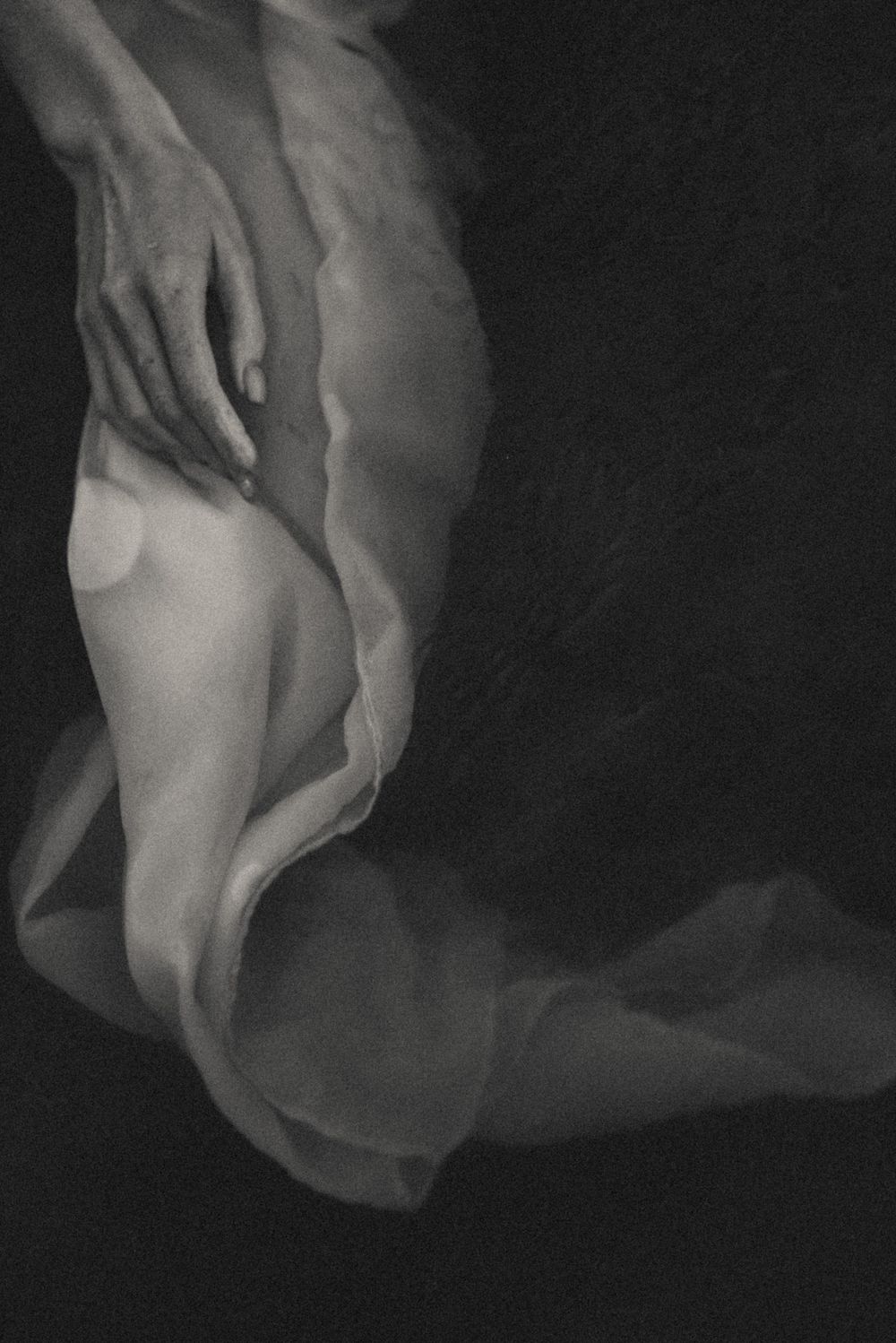 Abstract artistic study of flowing white fabric against dark background.