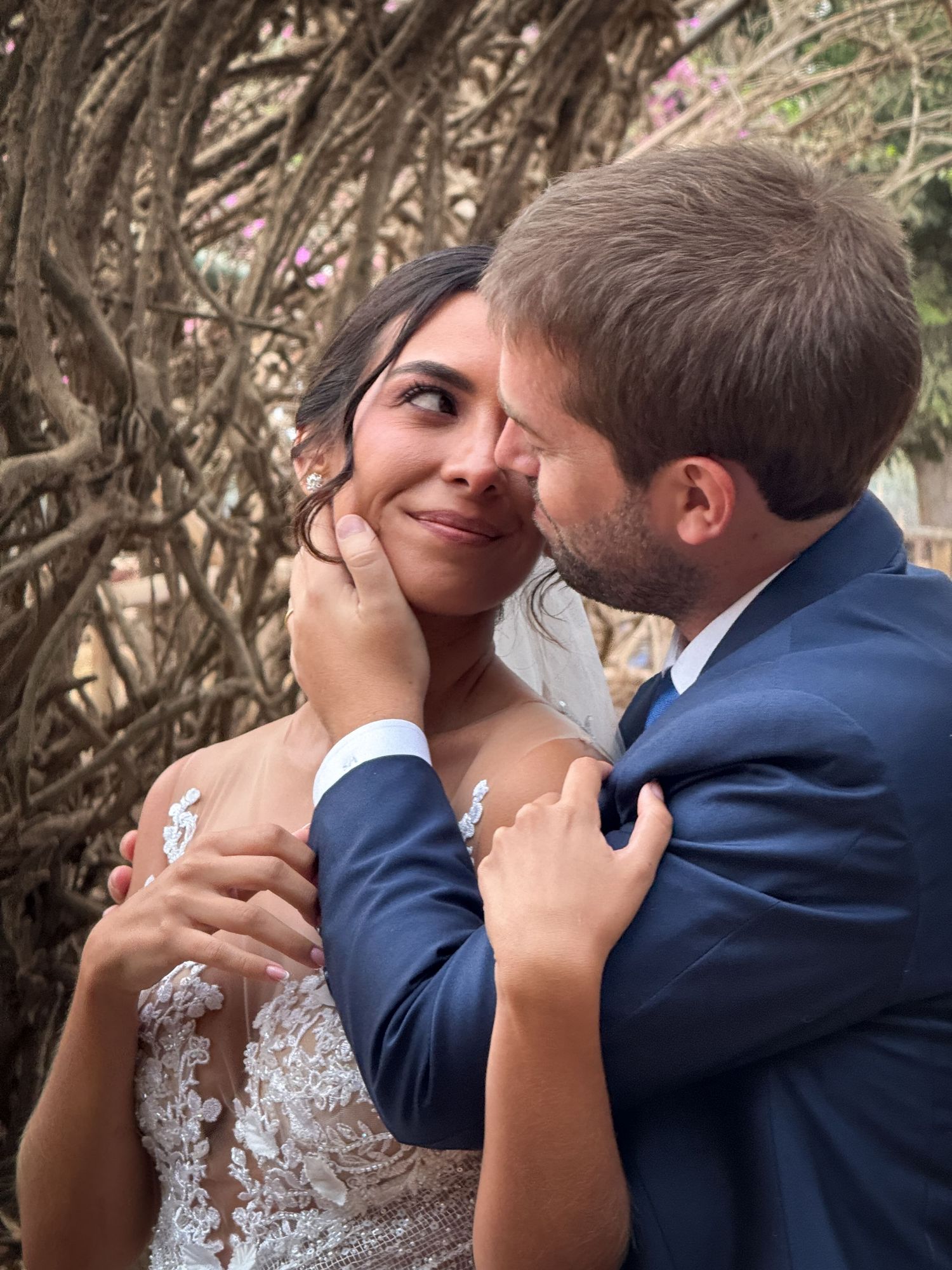 Intimate romantic moment captured between couple in wedding attire outdoors.