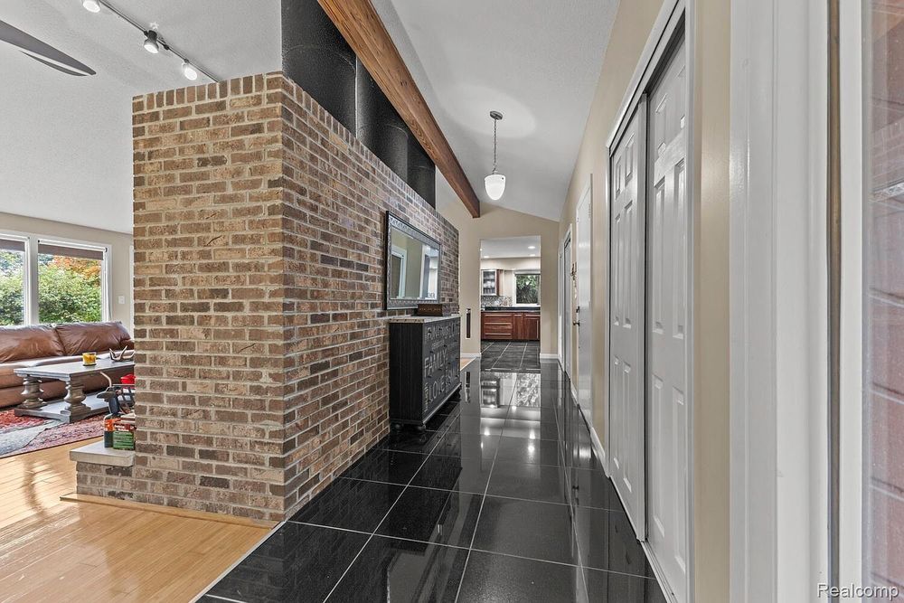 Interior hallway with black tile floors, exposed brick column, and track lighting.