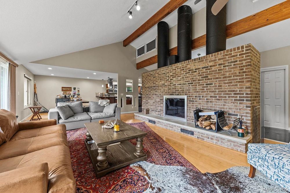Open living room with high vaulted ceilings, exposed beams, and floor-to-ceiling brick fireplace.