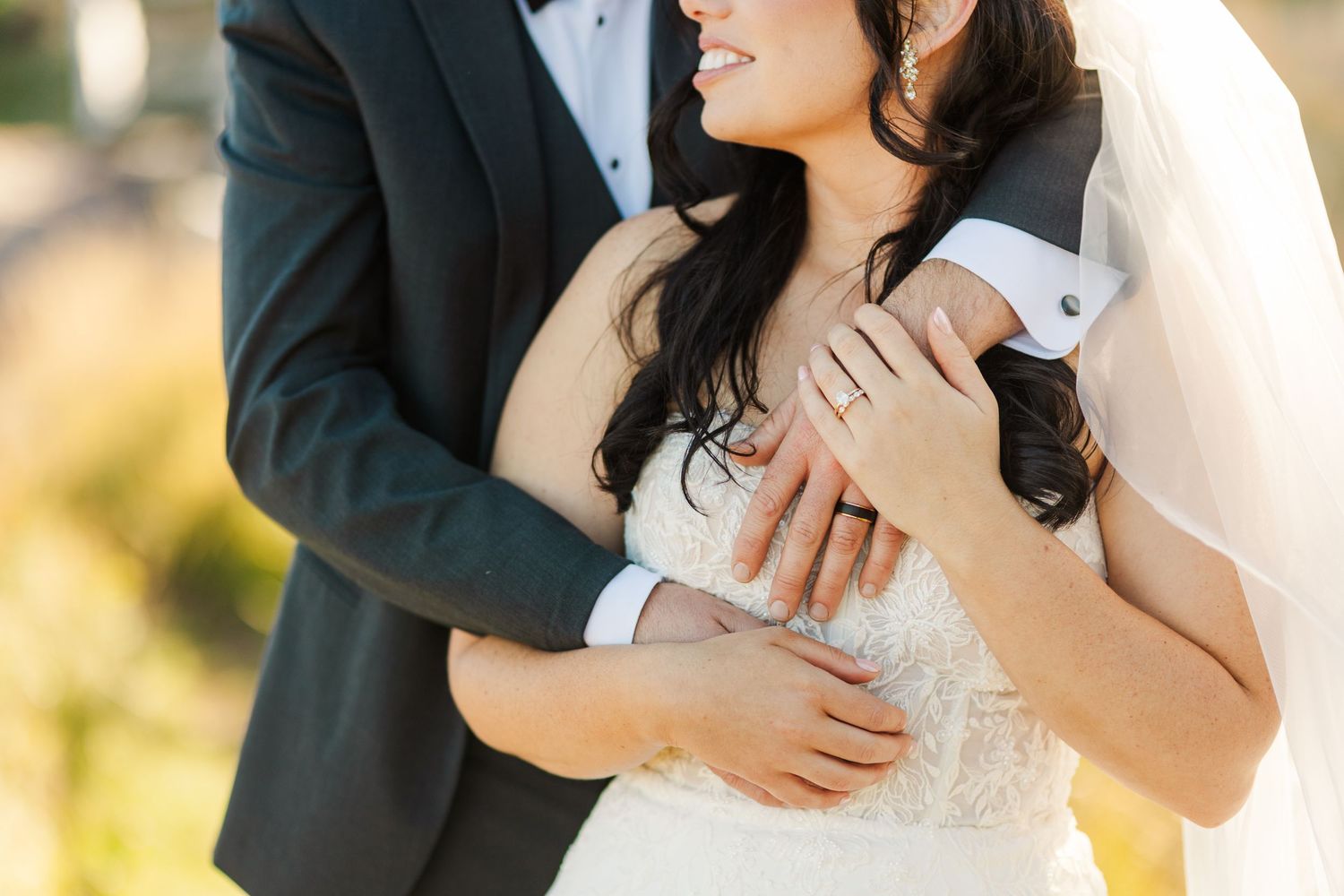 Close up shot of a couple embracing outdoors on their wedding day with soft natural lighting.