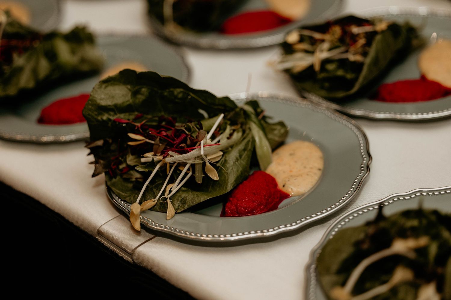 A collection of table settings with red and white plates arranged on a rustic surface with dried greenery accents.