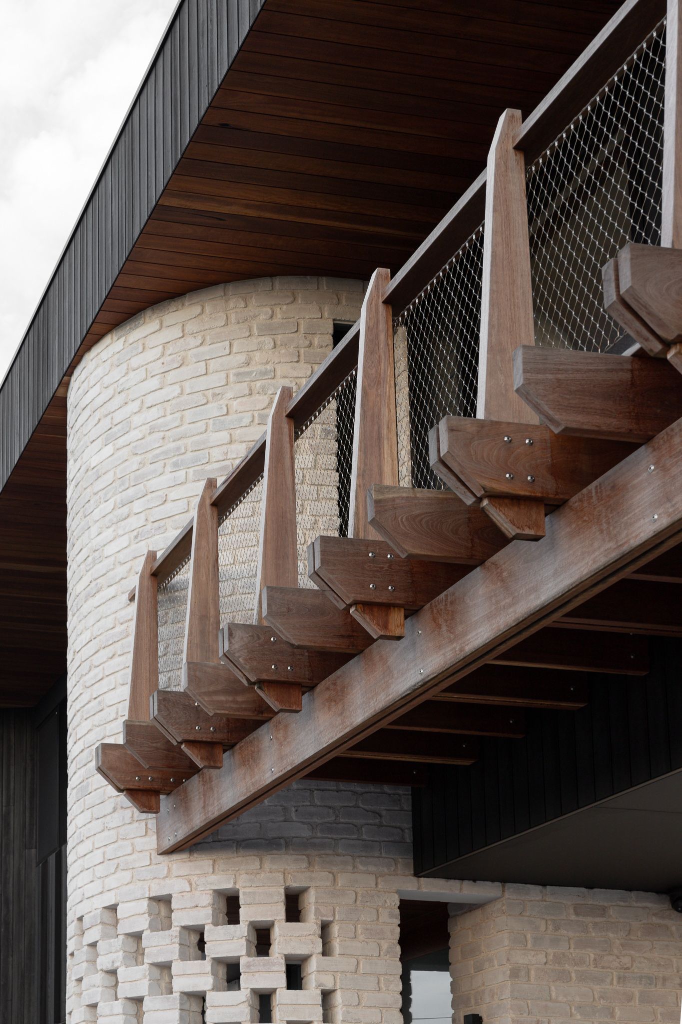 Architectural detail of rustic steel brackets and wooden beams against white stone wall.