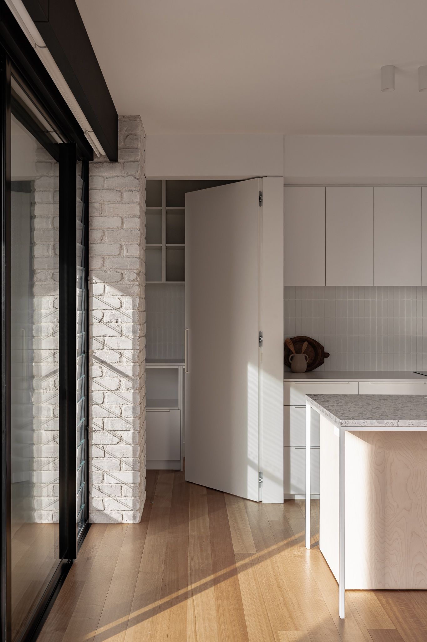 Bright interior hallway with white walls, timber flooring and floor-to-ceiling windows.