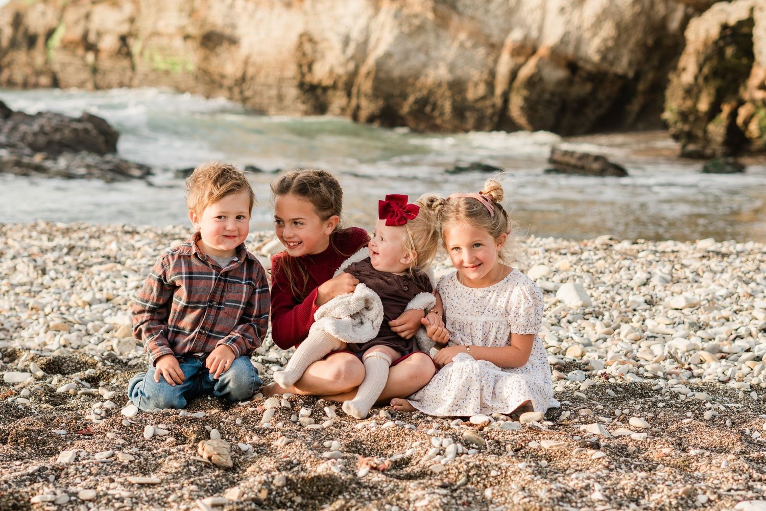 siblings sitting together for fall family session on the beach at Montana de oro wearing fall colors