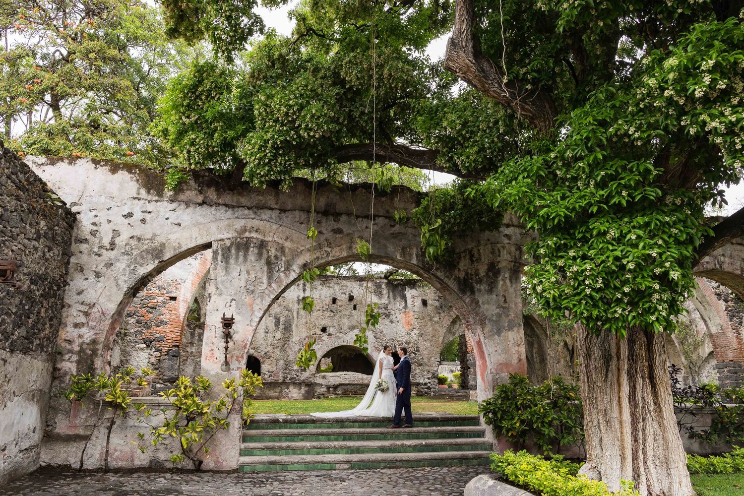 Stone archway garden path creates a romantic backdrop for a wedding ceremony.