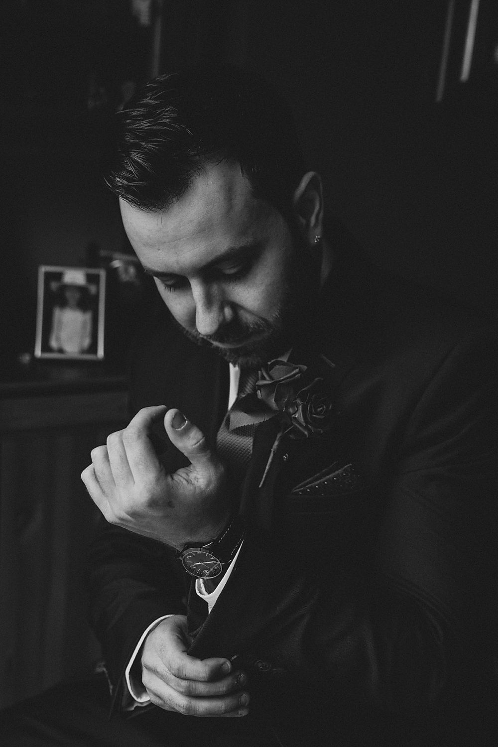 A series of black and white photographs showing groom getting ready in low light conditions.