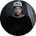 A person wearing a black jacket and beanie poses against a dark background in a casual portrait.