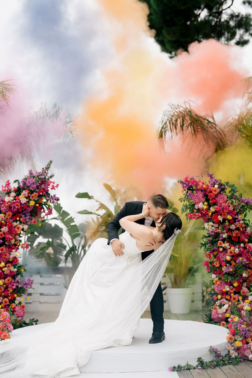 Romantic wedding photo shoot with colorful smoke bombs and floral arrangements creating a dreamy atmosphere.