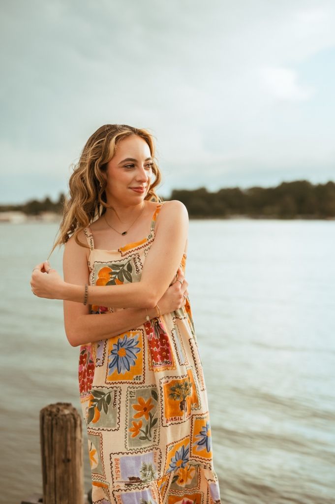 A summer photoshoot on a dock featuring a floral patterned sundress against a waterfront backdrop.