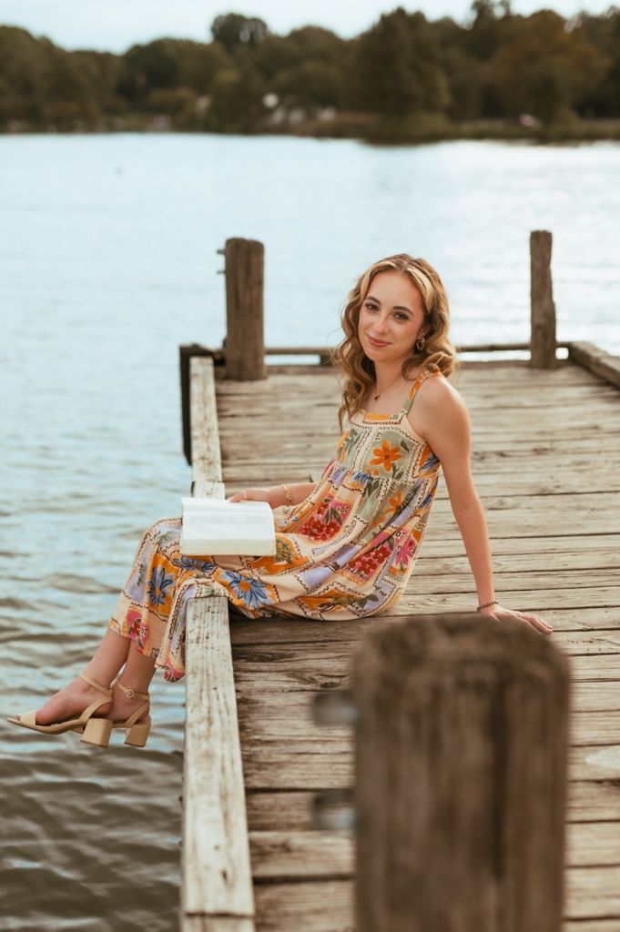 Lifestyle portrait on a wooden dock with a colorful printed maxi dress and book.