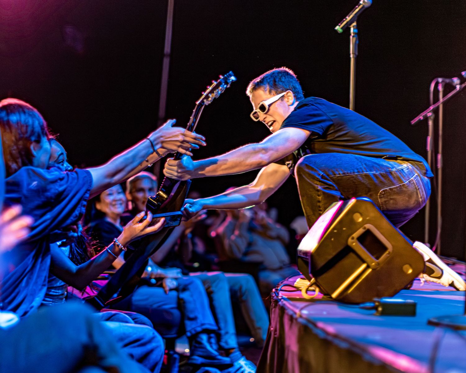 Musician performs on stage with electric guitar at Orange County School of the Arts under colorful lighting.