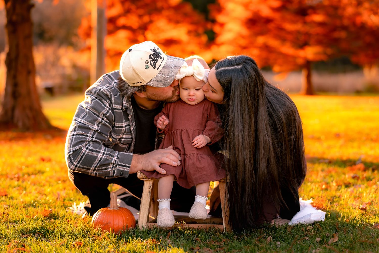 Family enjoying a fall photoshoot outdoors with pumpkins and autumn colors.
