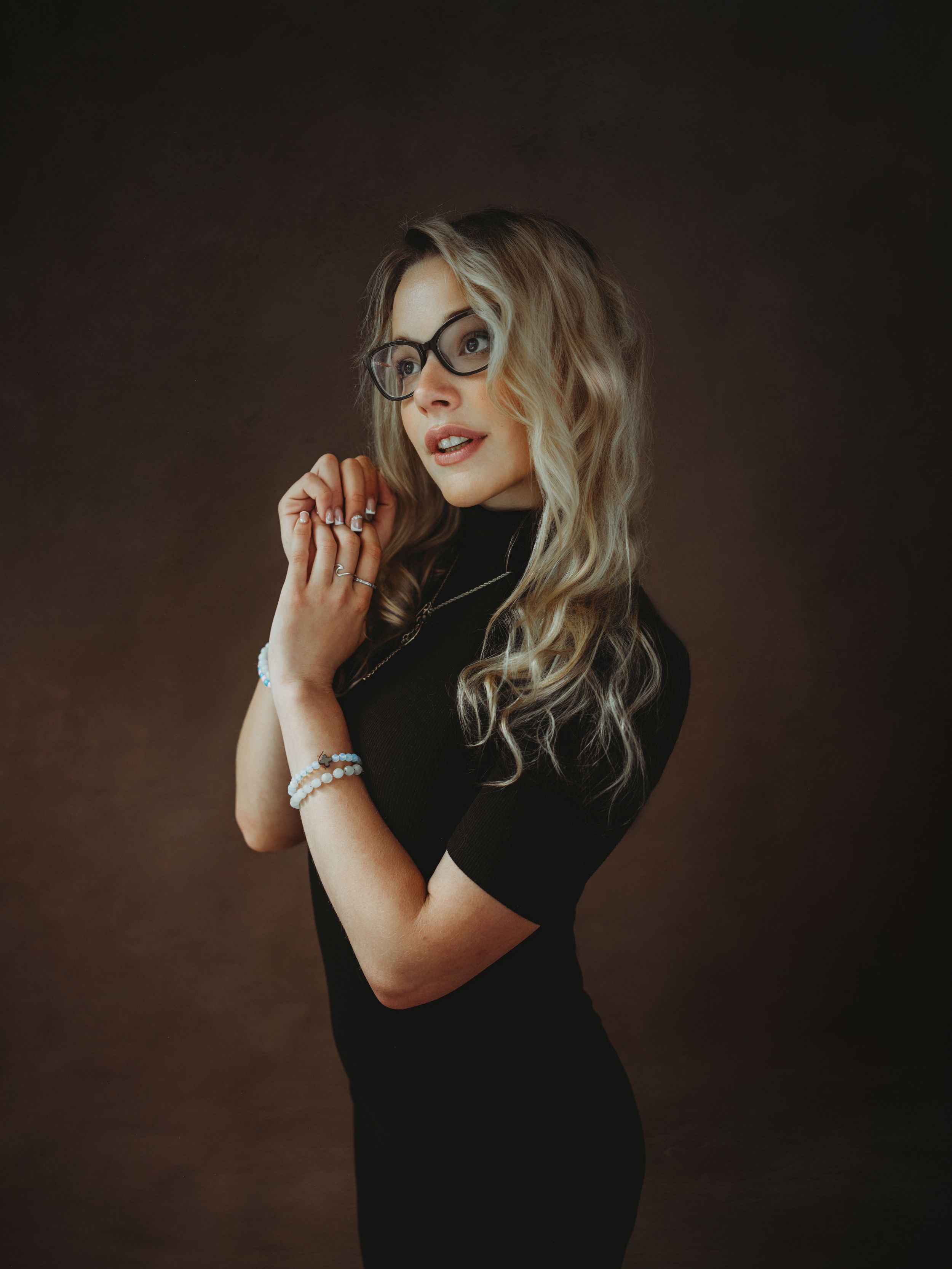 A moody portrait series of someone in a black top against a dark background, showing different poses and expressions.