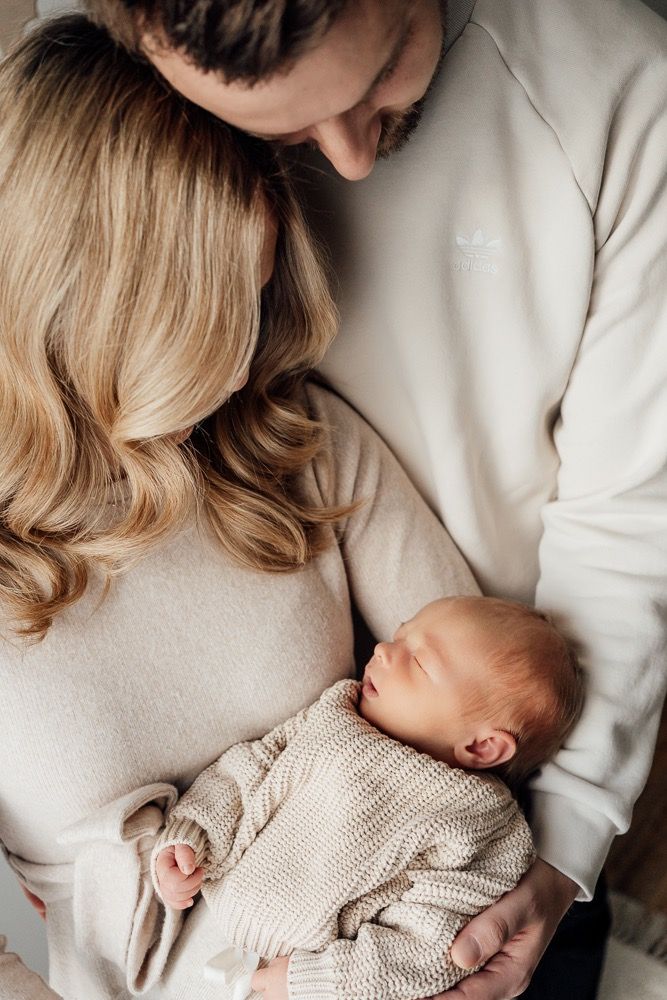 A series of intimate close-up shots showing tender moments with a sleeping newborn in a knit sweater.