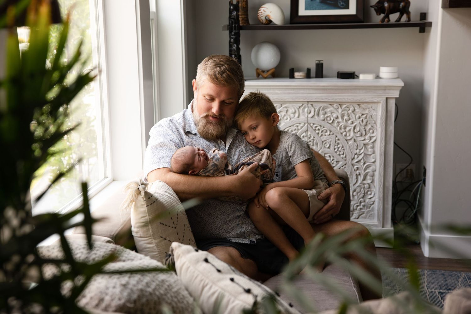 Parent and child share a tender moment while cuddling together on a cozy window seat with natural light streaming in.