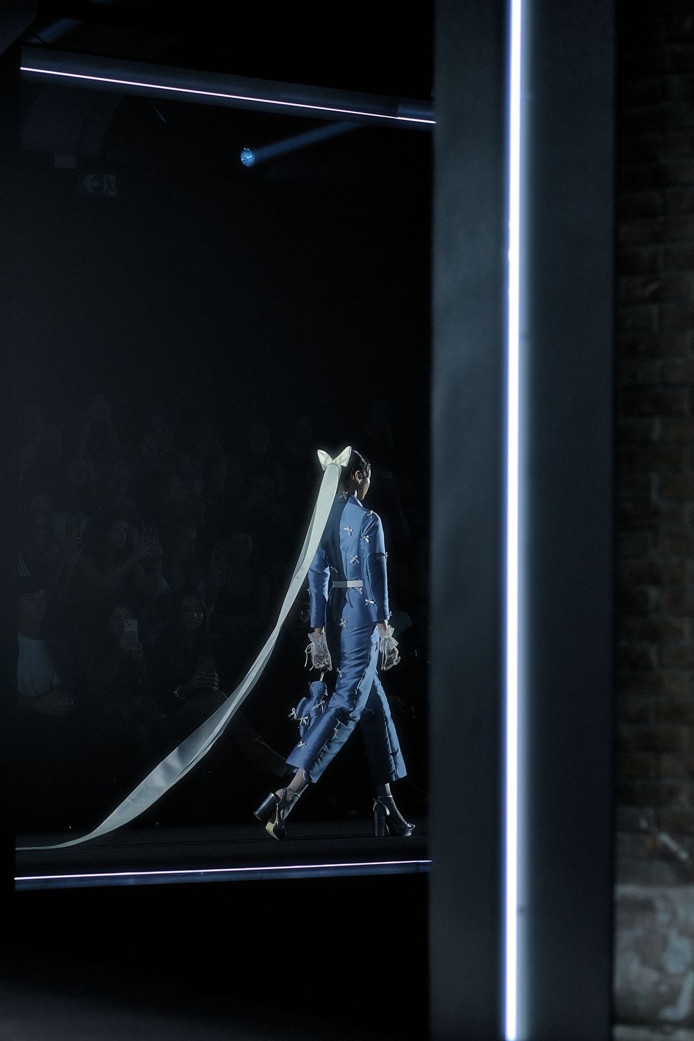 A pair of worn blue jeans hangs suspended against a dark background with dramatic lighting.