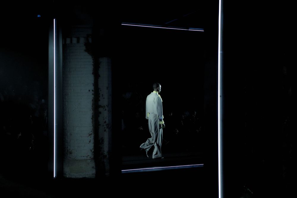 A dark and moody sequence of film stills showing a figure moving through dimly lit interior spaces.