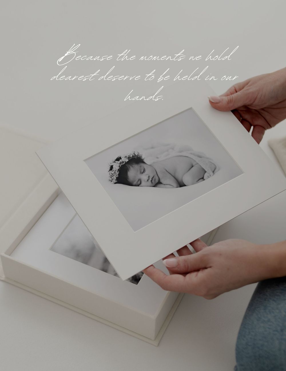 Hands gently holding a matted black and white photograph from an elegant photo album.