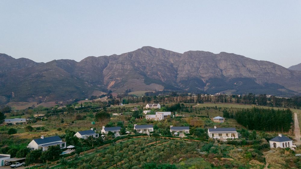 Panoramic mountain landscape with scattered white houses nestled among rolling hills and distant peaks.