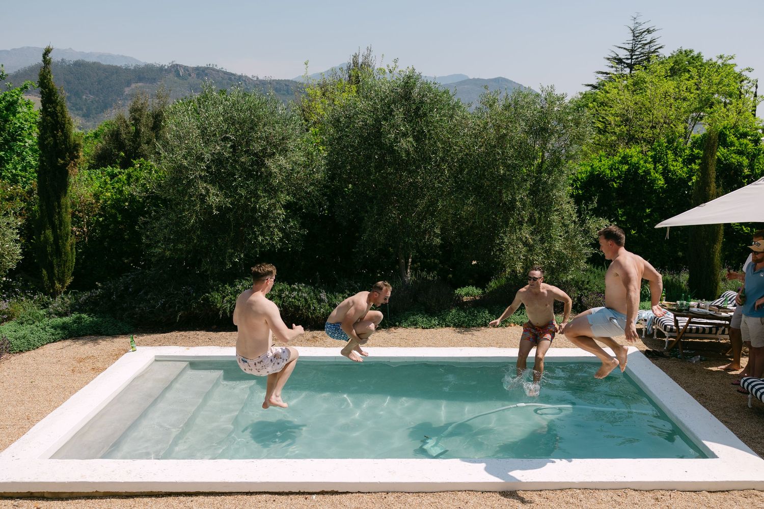 People enjoying a refreshing swim in a modern infinity pool with scenic mountain views in the background.