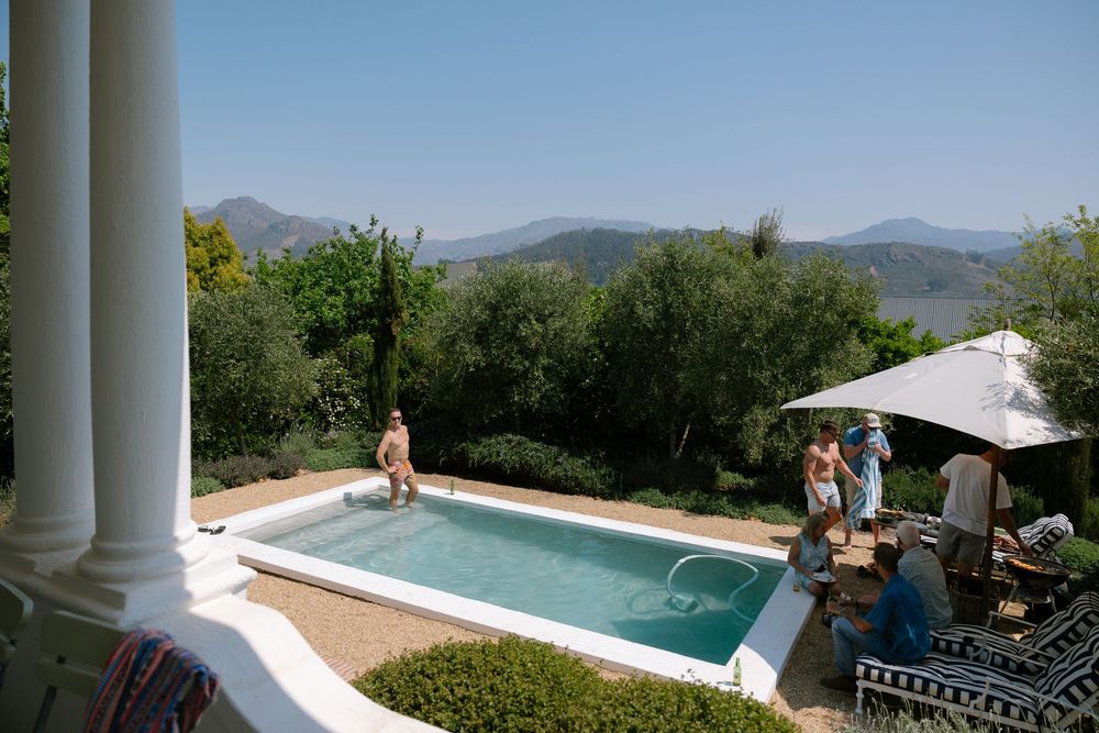 Scenic mountain views through white columns with an infinity pool overlooking a lush Mediterranean landscape.