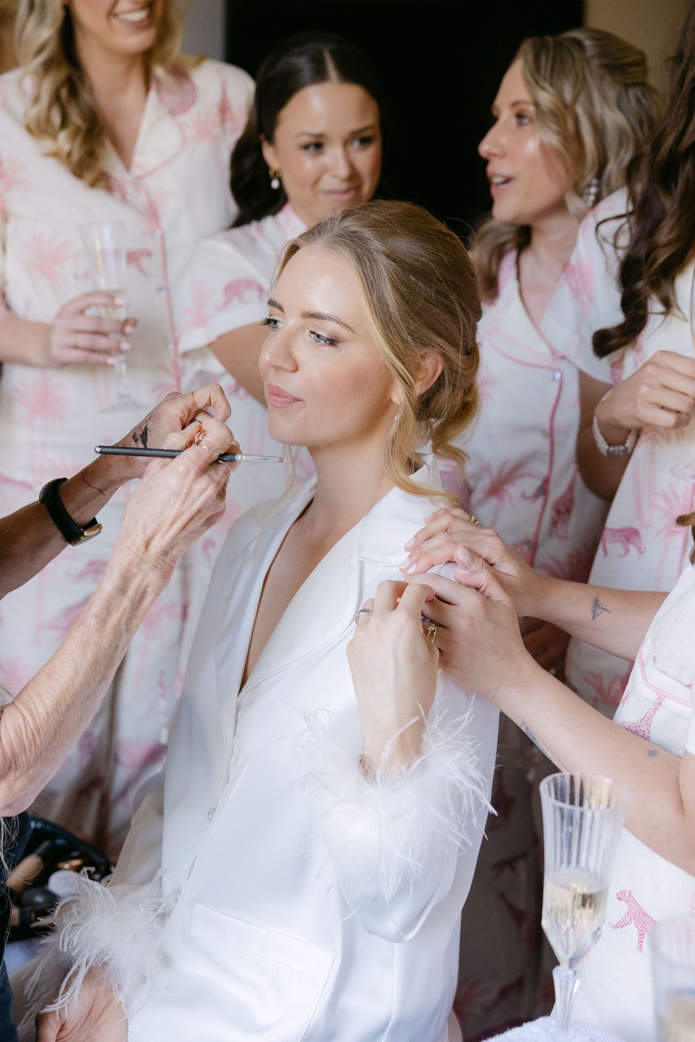 Wedding party getting ready in pink floral robes while having makeup and hair styled for the big day.