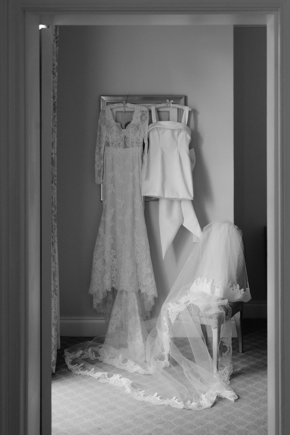 Multiple elegant white wedding dresses displayed on hangers in a bridal suite.
