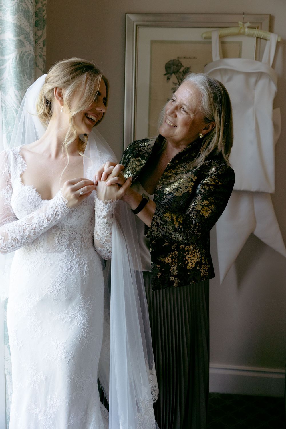 A tender moment shared while getting ready in a white lace wedding gown.
