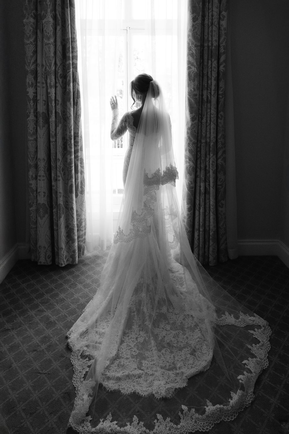 A series of black and white silhouettes showing a bride in a flowing lace wedding gown and veil by a window.