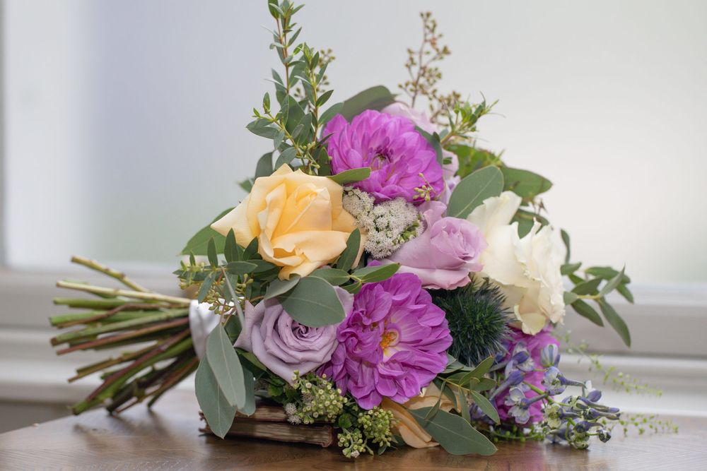 A collection of floral arrangements featuring roses, chrysanthemums, and greenery in soft purple, peach and white tones.