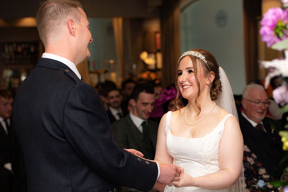 A happy couple shares their first dance at an elegant wedding reception surrounded by guests and floral decorations.