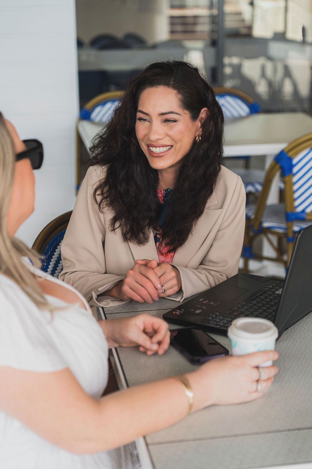 Professional meeting between two people at a desk with laptop and coffee cup showing friendly interaction and discussion.