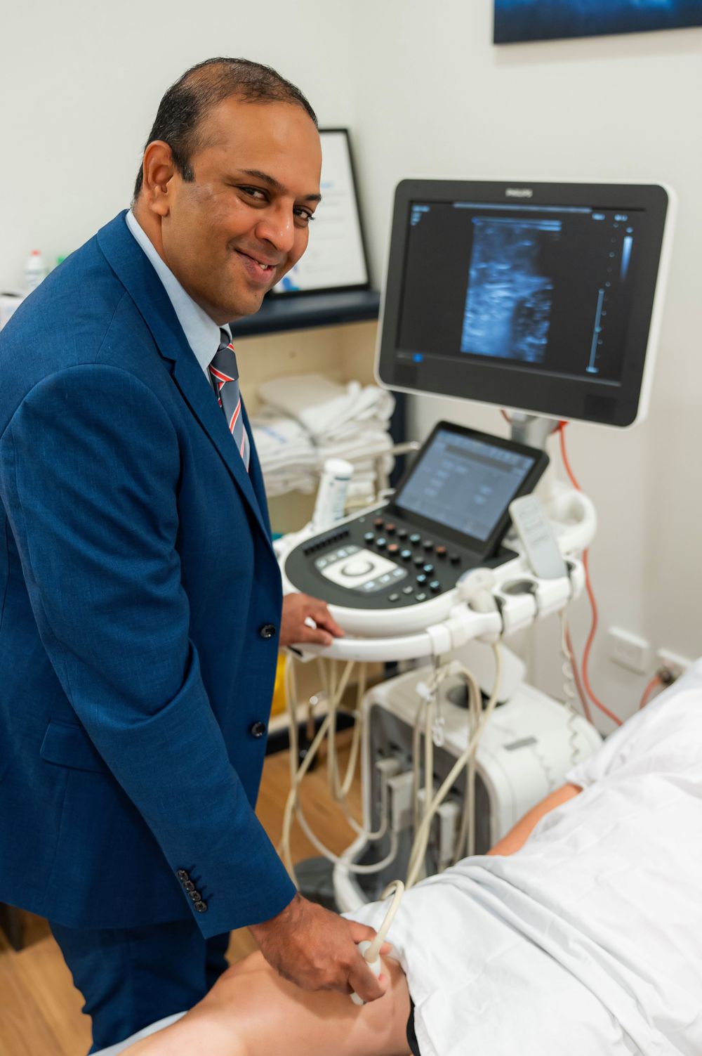 Medical professional in blue suit performs ultrasound scan with modern equipment in clinical setting.