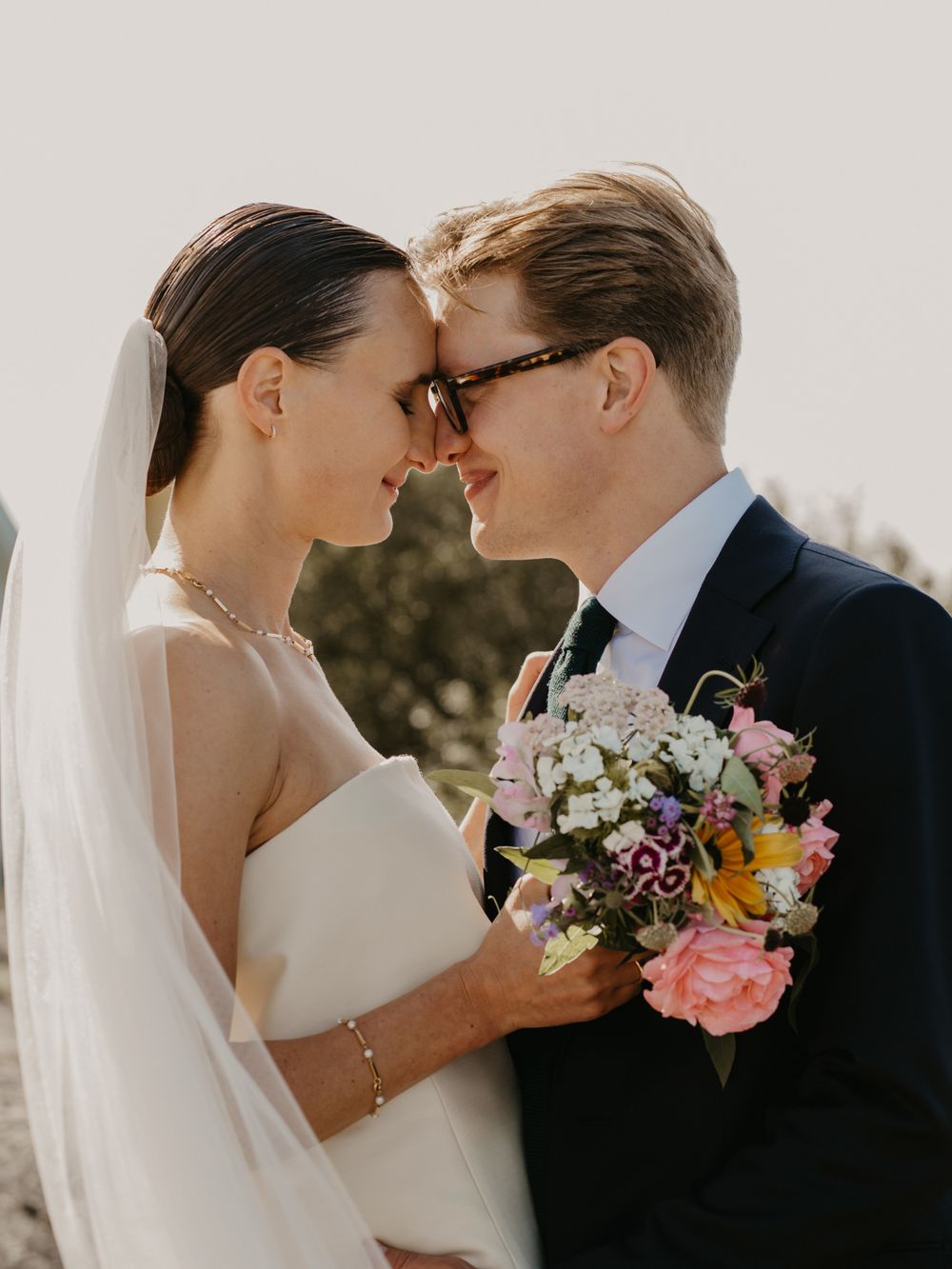 A romantic wedding couple shares intimate moments in a series of tender poses with soft floral bouquet details.