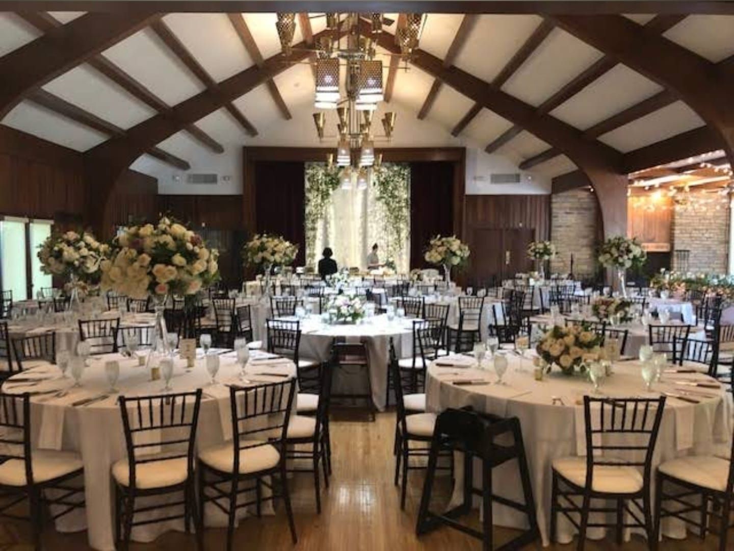 Elegant wedding reception venue with dark wood beams and crystal chandeliers.