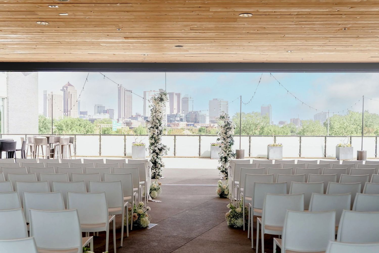 Modern wedding ceremony venue interior with rows of white chairs and wooden beam ceiling details.