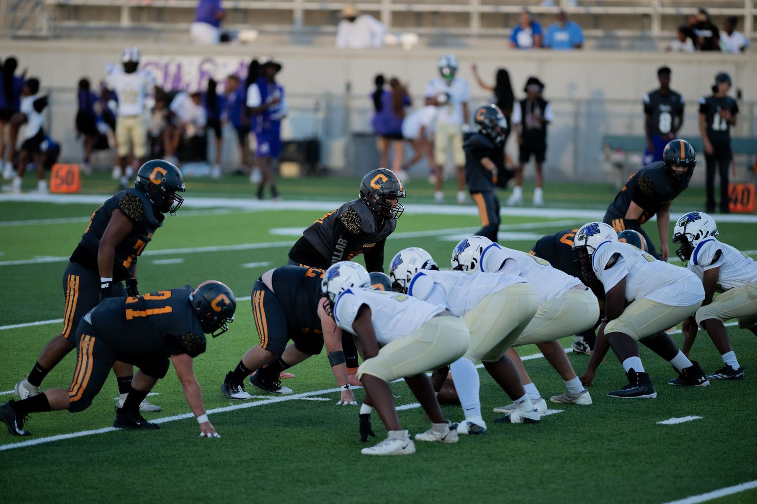 Football teams line up at the line of scrimmage before the snap during a competitive game.