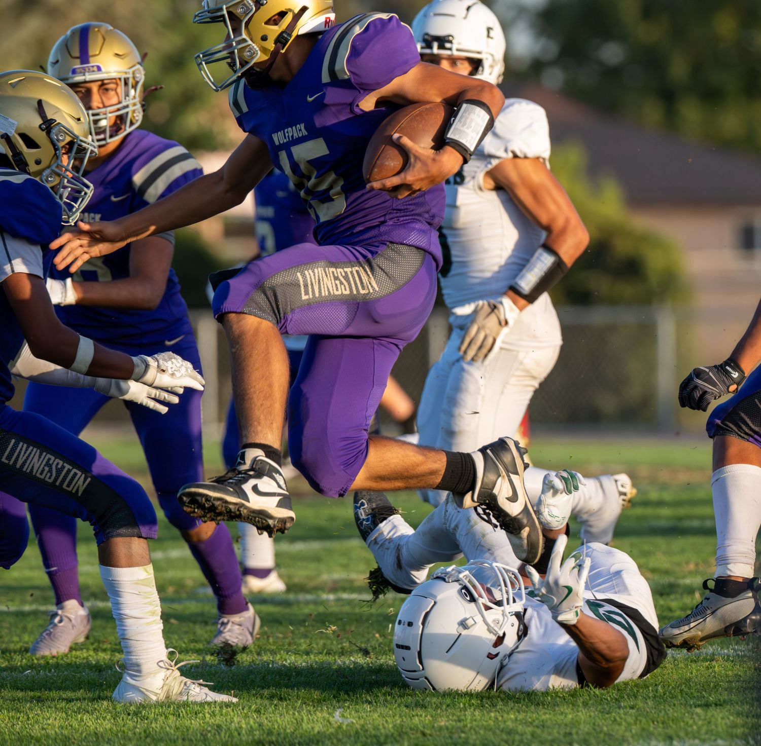 Football players from opposing teams collide during a tackle attempt on the field.