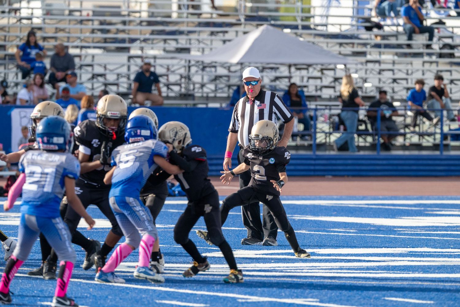 Football teams line up in formation on bright blue turf during an afternoon game.