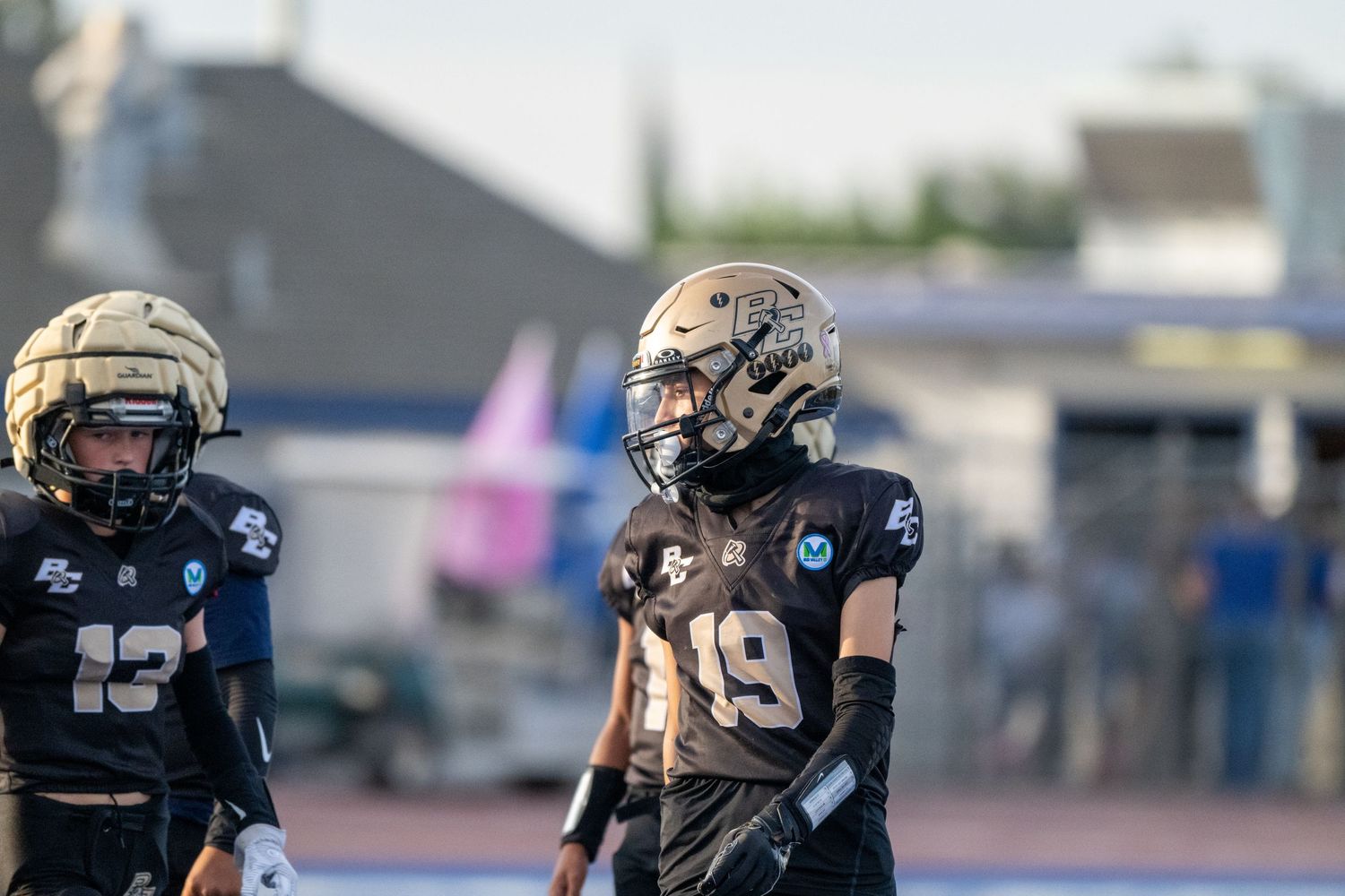Football players in gold and black uniforms line up on a blue field during a game.