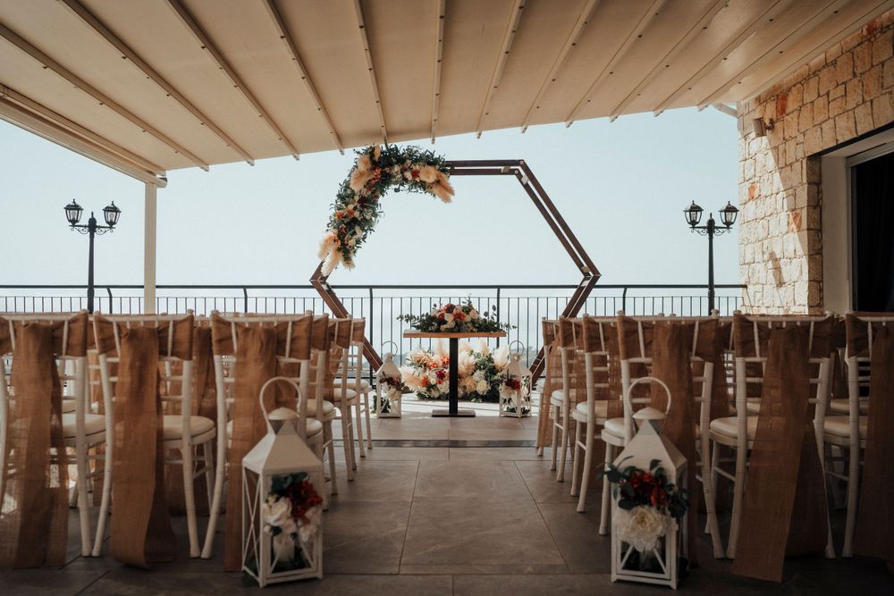 A decorated wedding ceremony space with floral hexagon arch and rustic chair decorations.