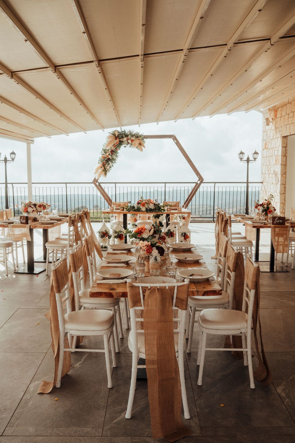 Elegant outdoor wedding reception setup with hexagonal arch and mountain view.