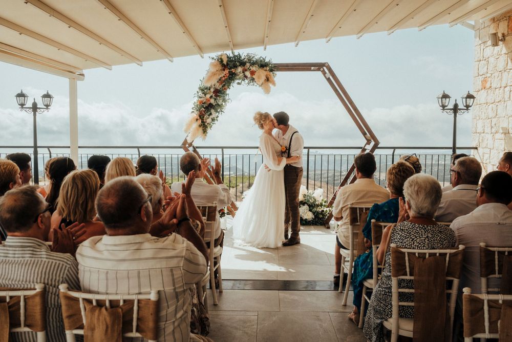 An intimate wedding ceremony under a hexagonal arch on a covered oceanfront terrace.