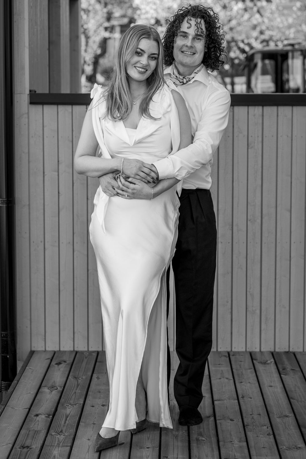 A black and white portrait showcasing elegant formal attire on a wooden deck.