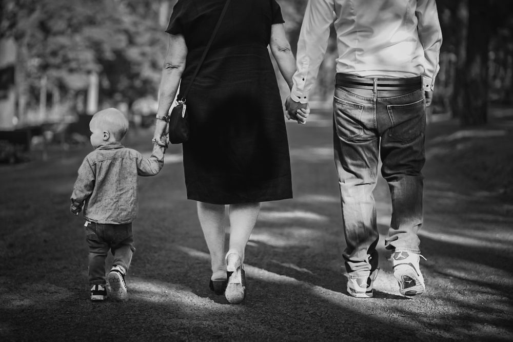 Black and white image of three people walking together on a path.